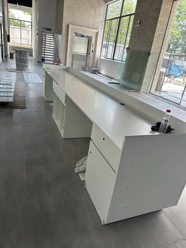 Quầy dài cánh trắng đang lắp, kính và vật tư còn dưới sàn