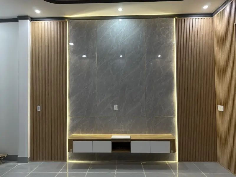 Vách tivi ốp tấm PVC vân đá xám, LED hắt viền, kệ tivi treo màu trắng mặt vân gỗ, hai bên ốp lam vân gỗ