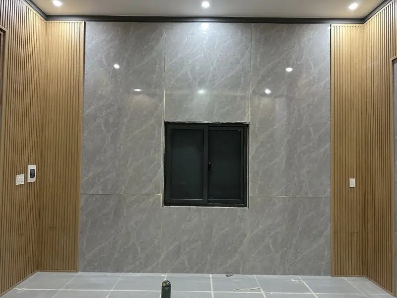 Tường đối diện cùng phòng ốp PVC vân đá xám quanh cửa sổ, hai bên lam vân gỗ